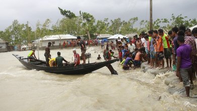 20.05.2020, Bangladesch, Shyamnagar: Ein Boot bringt vor der Ankunft des Zyklons «Amphan» Menschen ans Land, während Einheimische einen Damm überprüfen. Der Wirbelsturm hat in Indien und Bangladesch über zehn Menschen das Leben gekostet. 