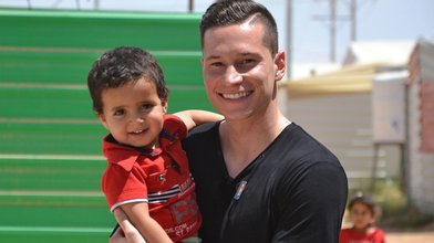 Julian Draxler mit einem syrischen Flüchtlingskind.